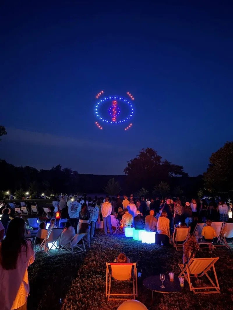 Motif bleu et rouge formé par les drones au-dessus du public
