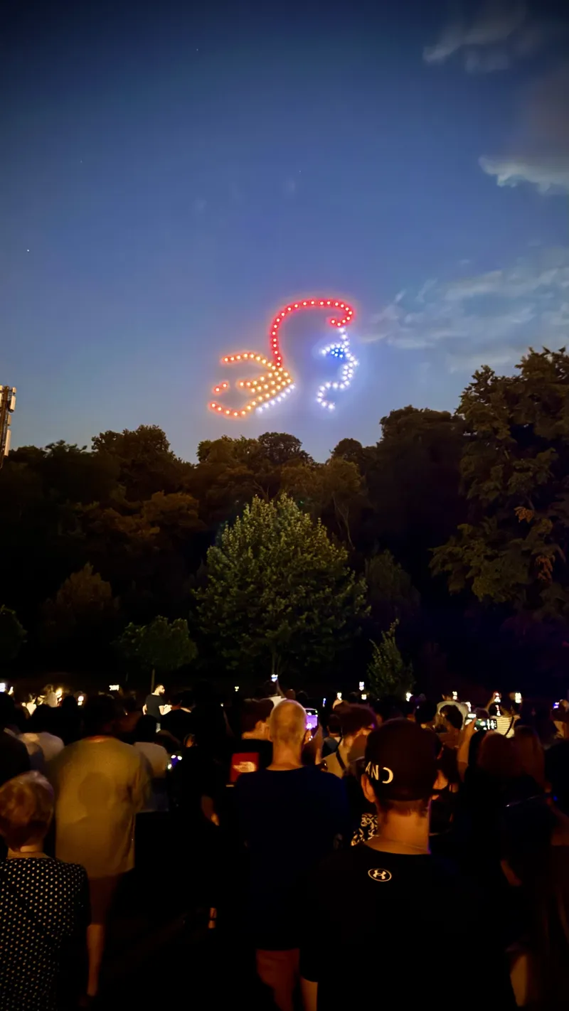 Figure rouge et blanche dessinée en drones lumineux au-dessus du public