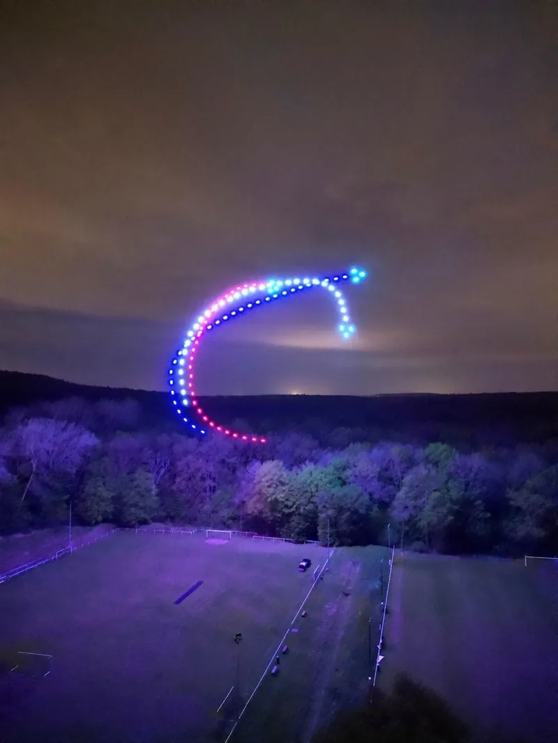 Trait courbe rouge et bleu dessiné dans le ciel par des drones lumineux