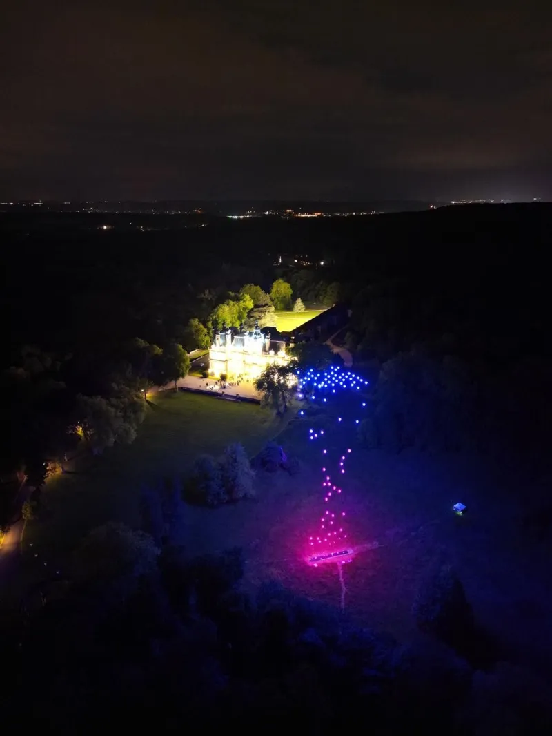Figure bleue et rose en drones lumineux au-dessus du parc du château