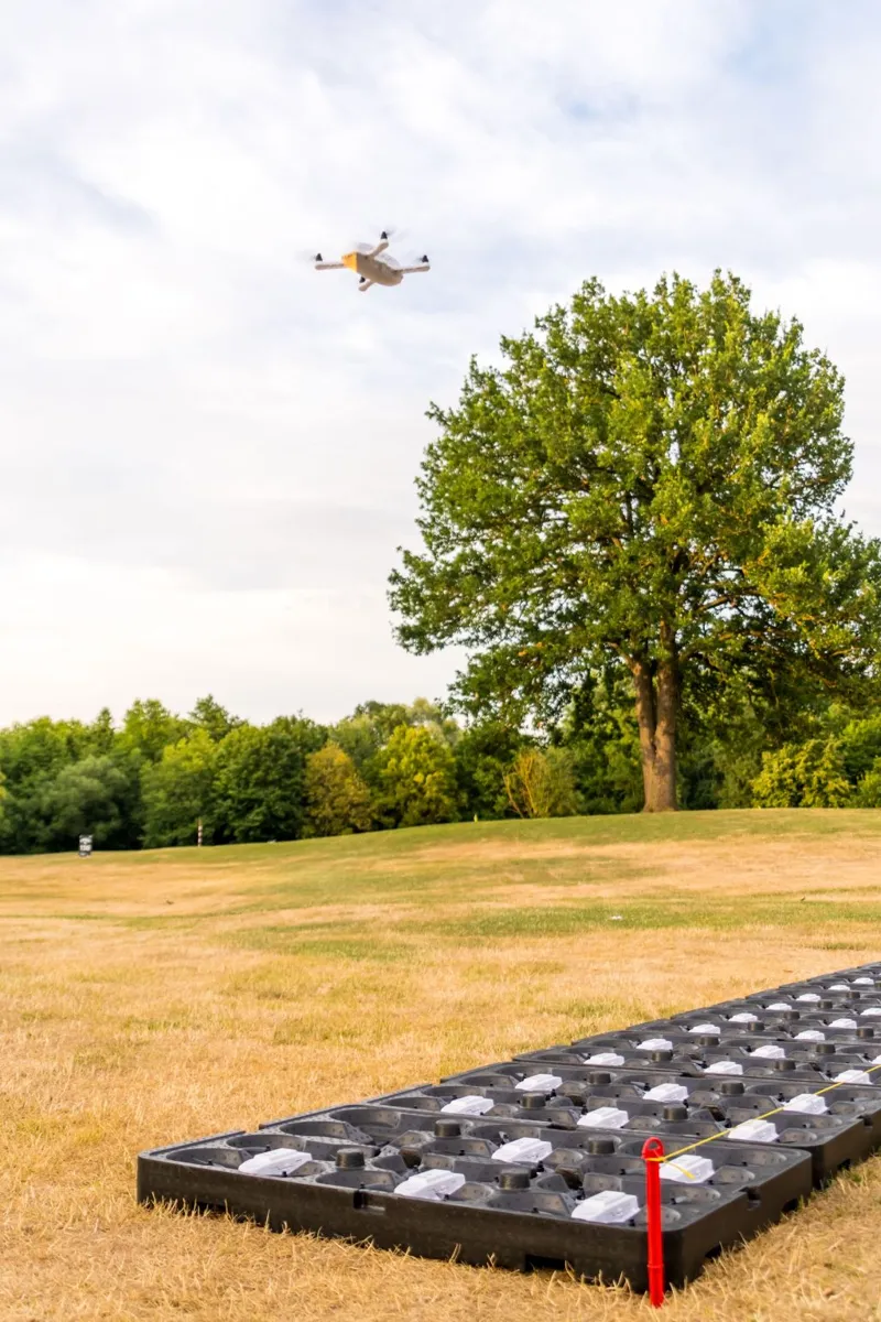Drone de test en vol au-dessus des plateaux de décollage posés sur l'herbe