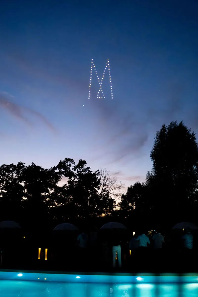 Lettre M du logo MGallery dessinée par les drones au-dessus de la piscine